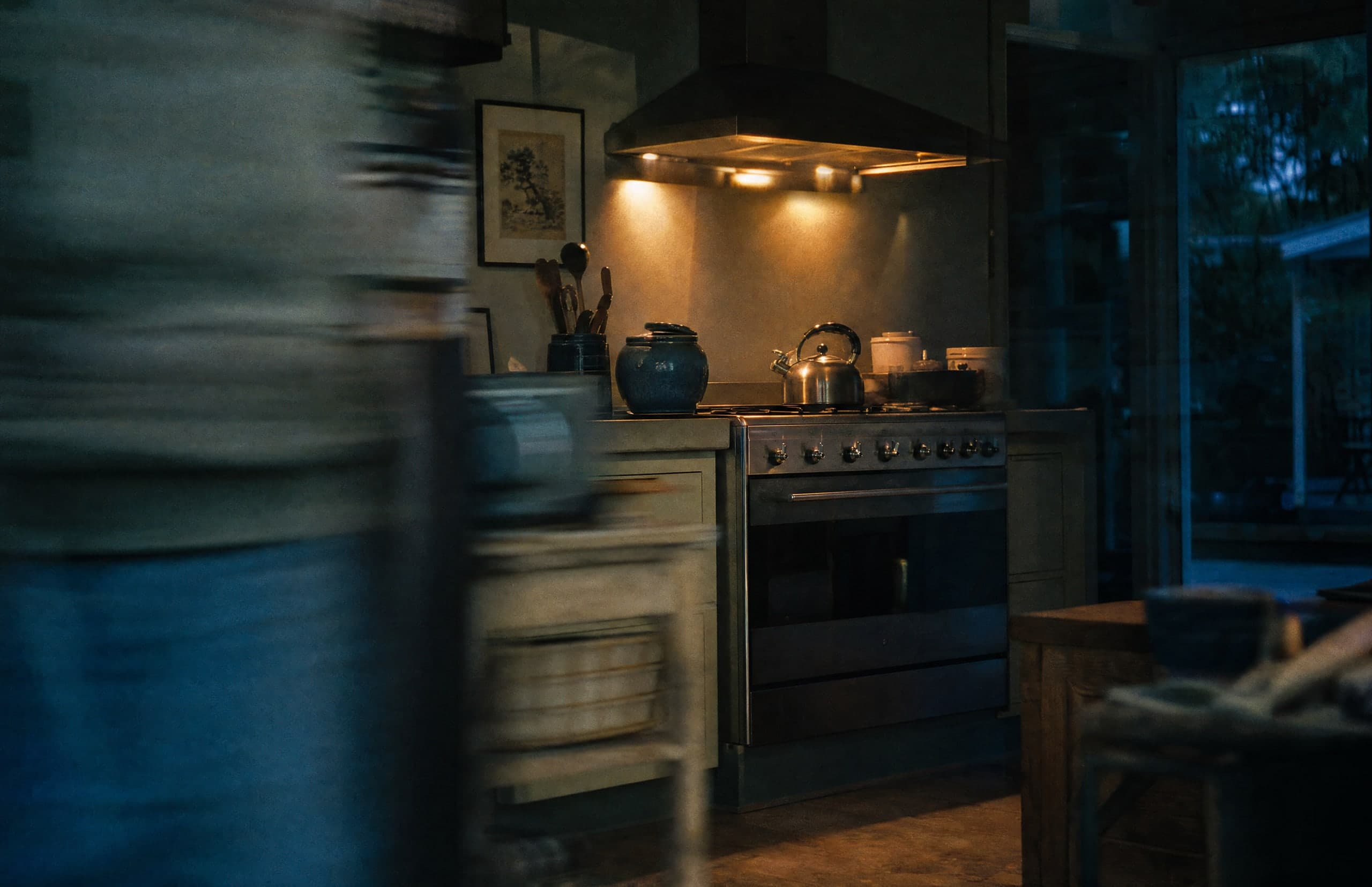 An oven and rangehood glowing in a home kitchen at dusk.