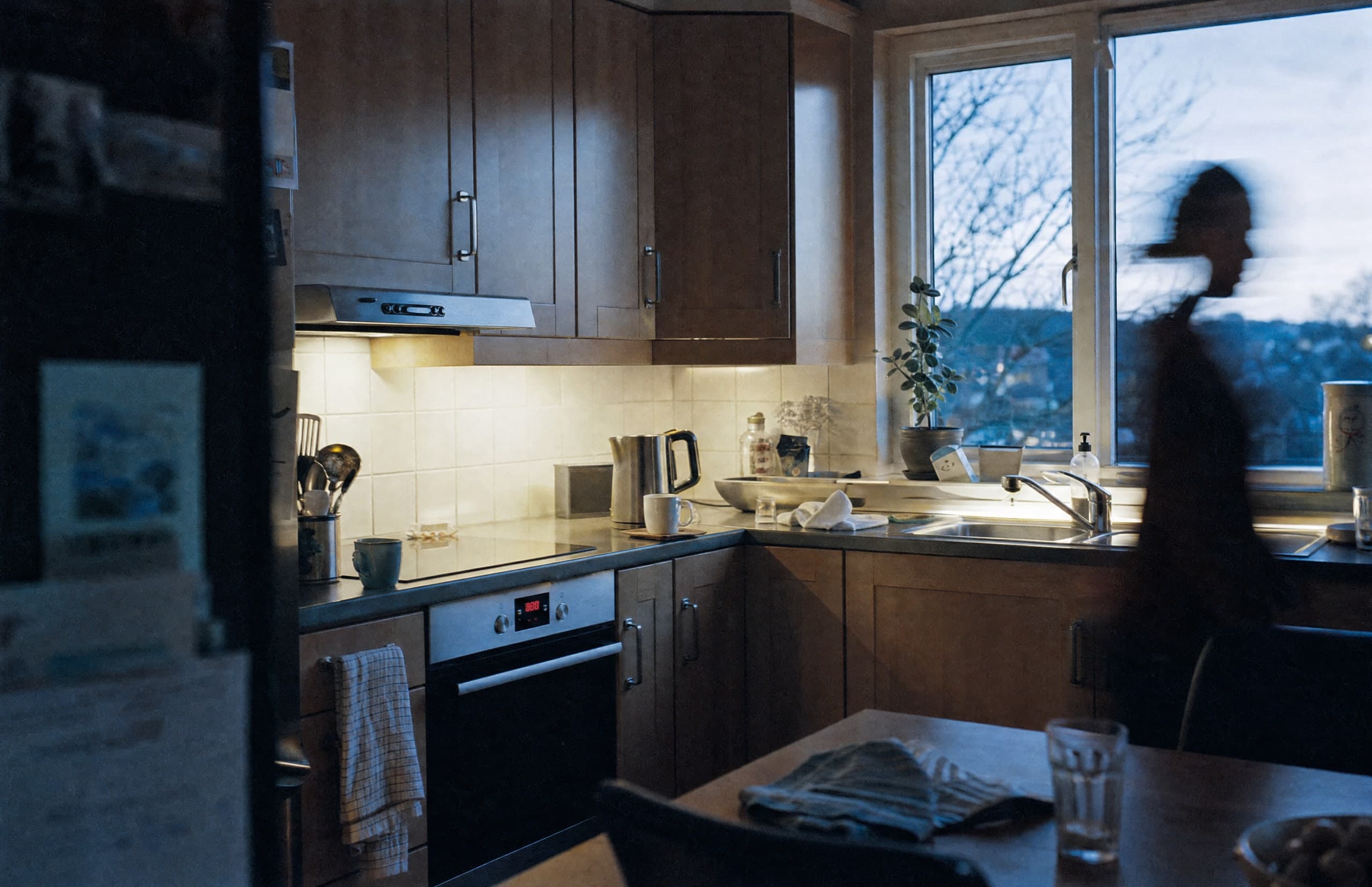 An evening kitchen with warm lighting and someone moving through the room.